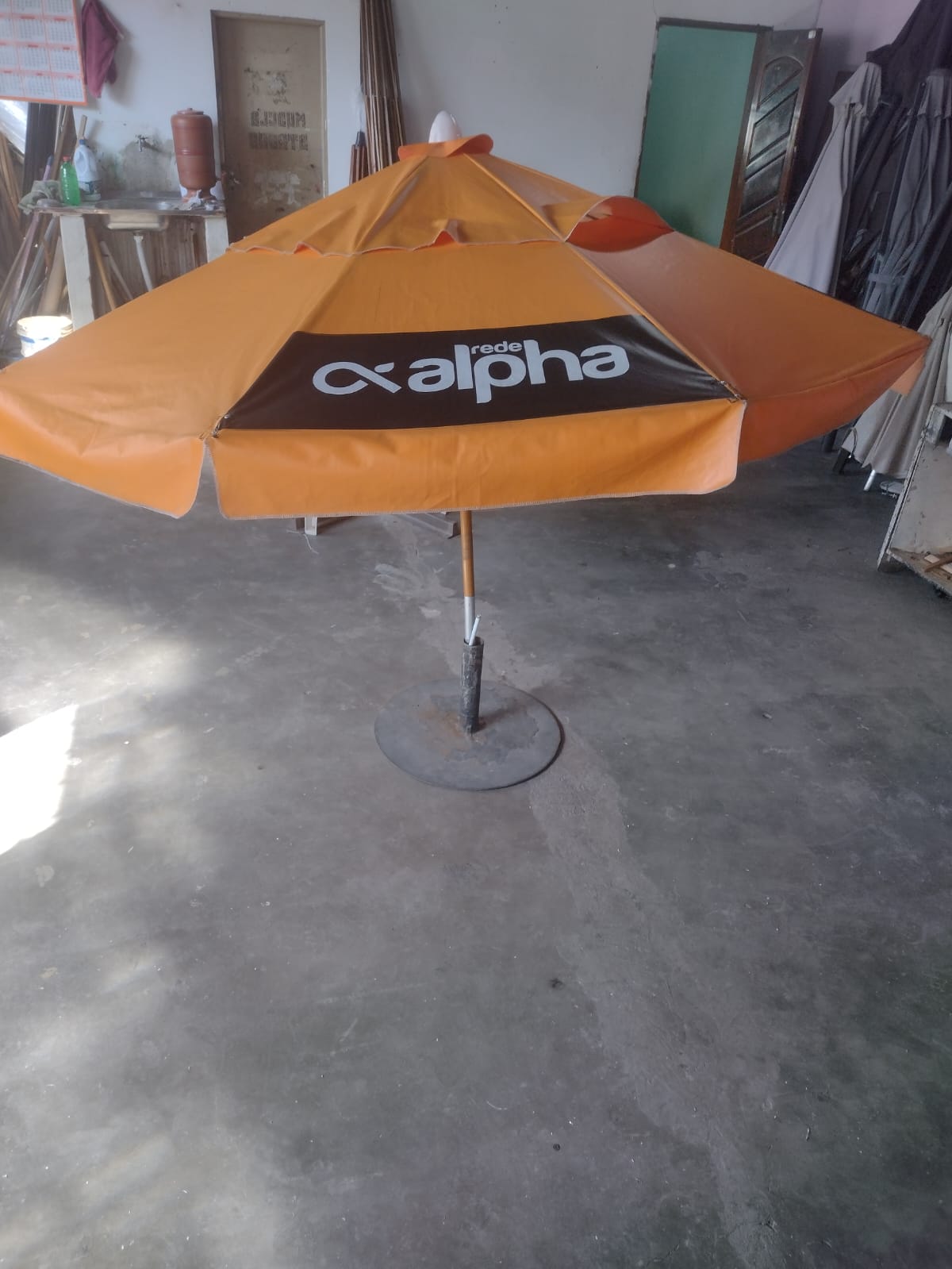Ombrelone com tecido laranja, personalizado com o logo da empresa Rede Alpha